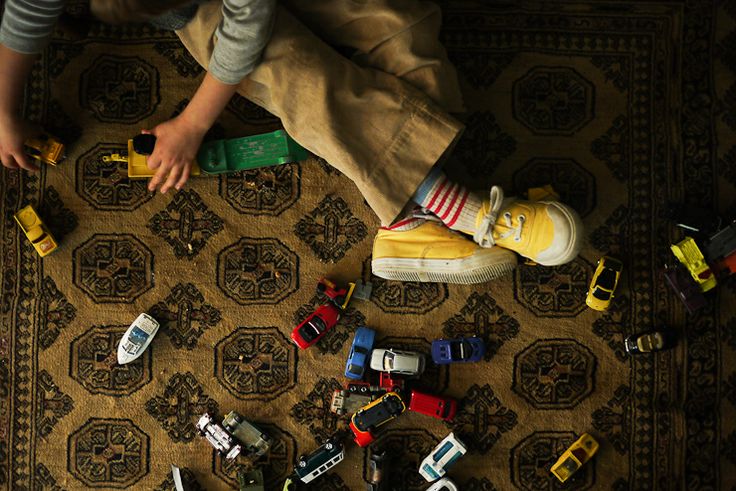 a young boy laying on top of a rug covered in toy cars and trucks next to each other