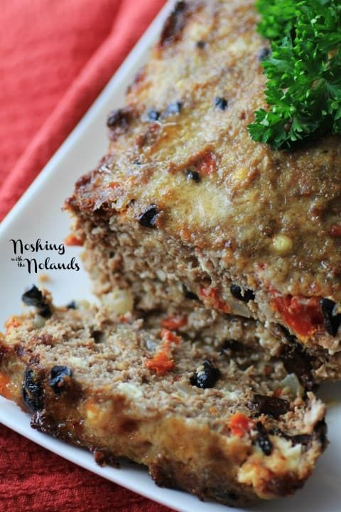 meatloaf with carrots, black olives and parsley on a white plate