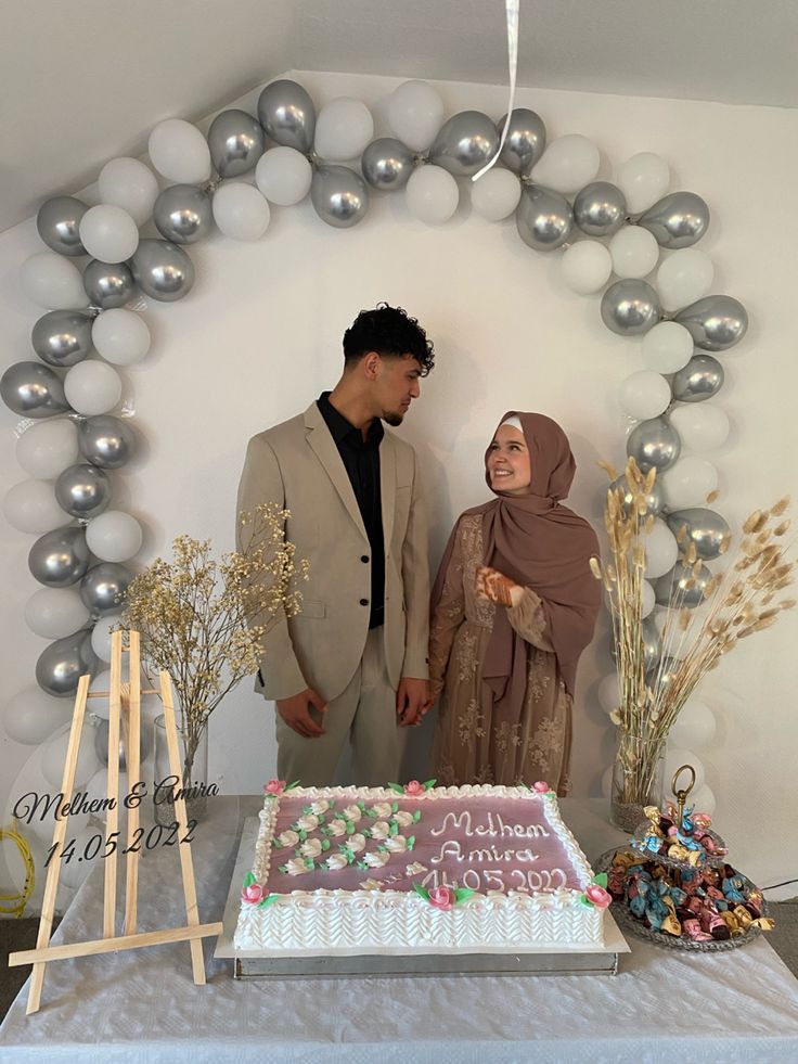 a man and woman standing next to a cake