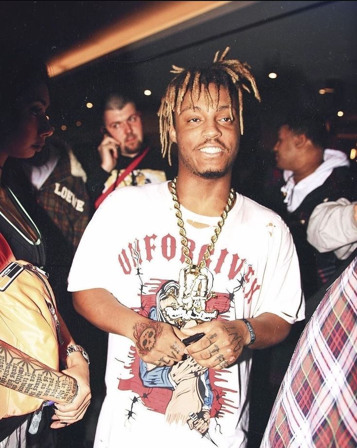 a young man with dreadlocks standing in front of other people at a party