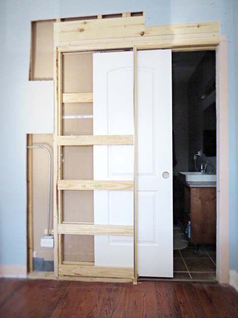 an empty room with wooden shelves and white doors in the center, next to a sink