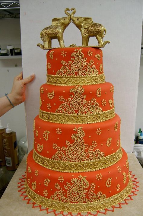 a three tiered cake with gold decorations on the top and bottom layer is orange