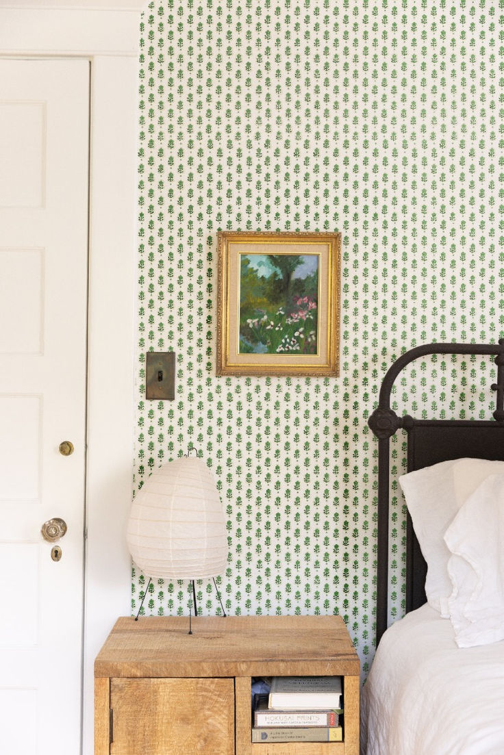 a bed room with a neatly made bed and a painting on the wall