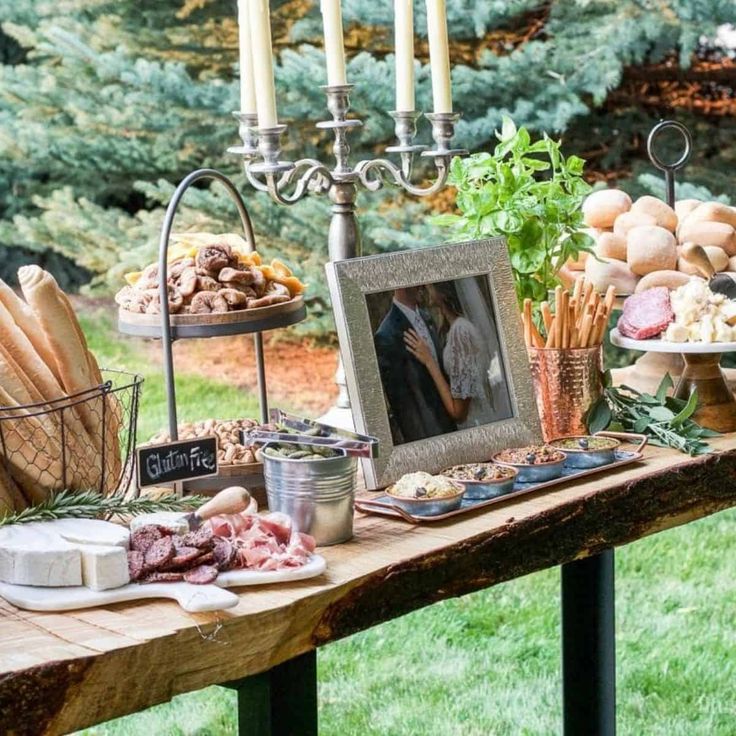 a wooden table topped with lots of food next to a tall candelabra