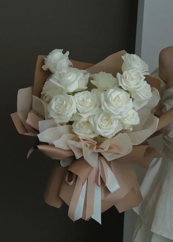 a bride holding a bouquet of white roses