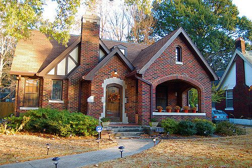 a brick house in the fall with leaves on the ground