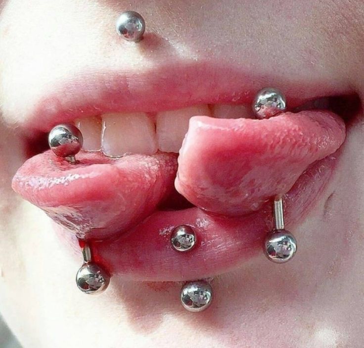 a close up of a person with piercings on their tongue