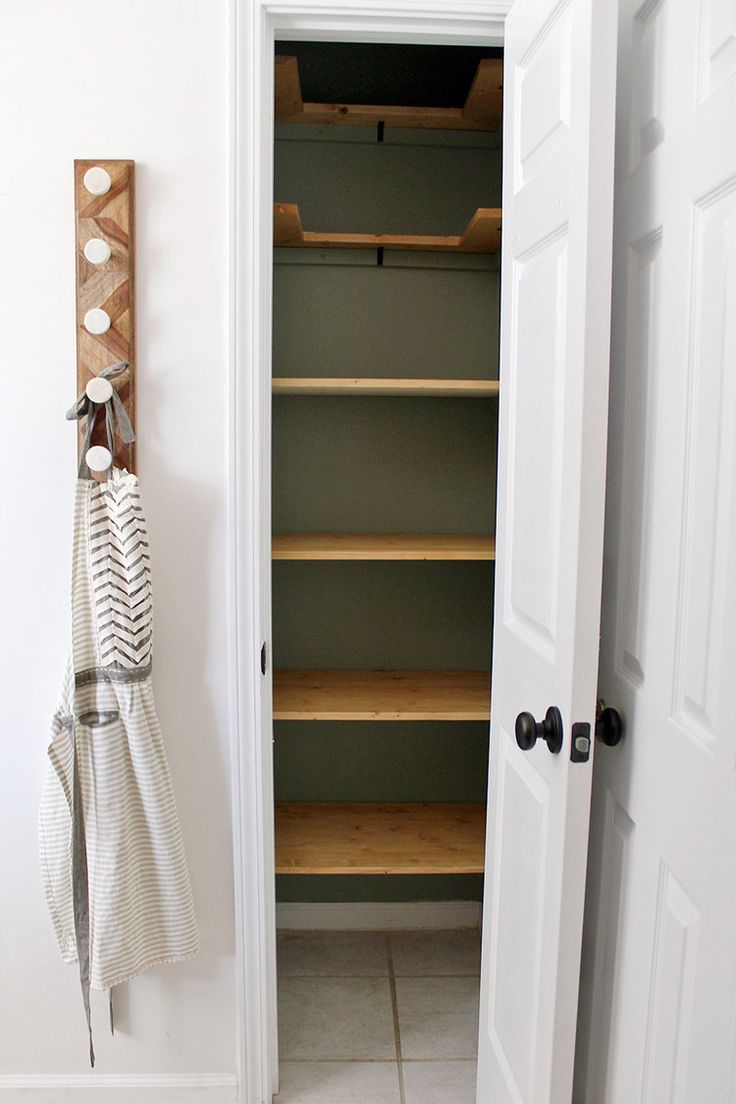 an open closet door with shelves and towels hanging on the wall next to two white doors