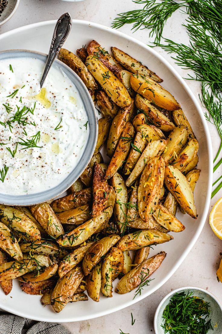 a white plate topped with fried asparagus next to a bowl of dip