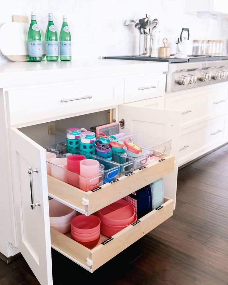 an open cabinet in a kitchen filled with dishes and cups on the bottom shelf is full of cleaning supplies