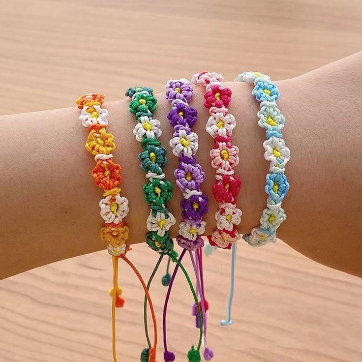 a person's arm with four bracelets on top of it and one is made out of multicolored beads