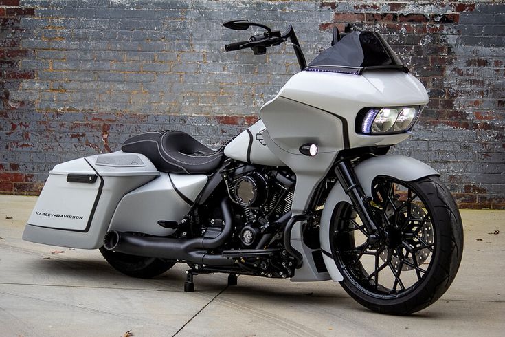 a white and black motorcycle parked in front of a brick wall with no one on it