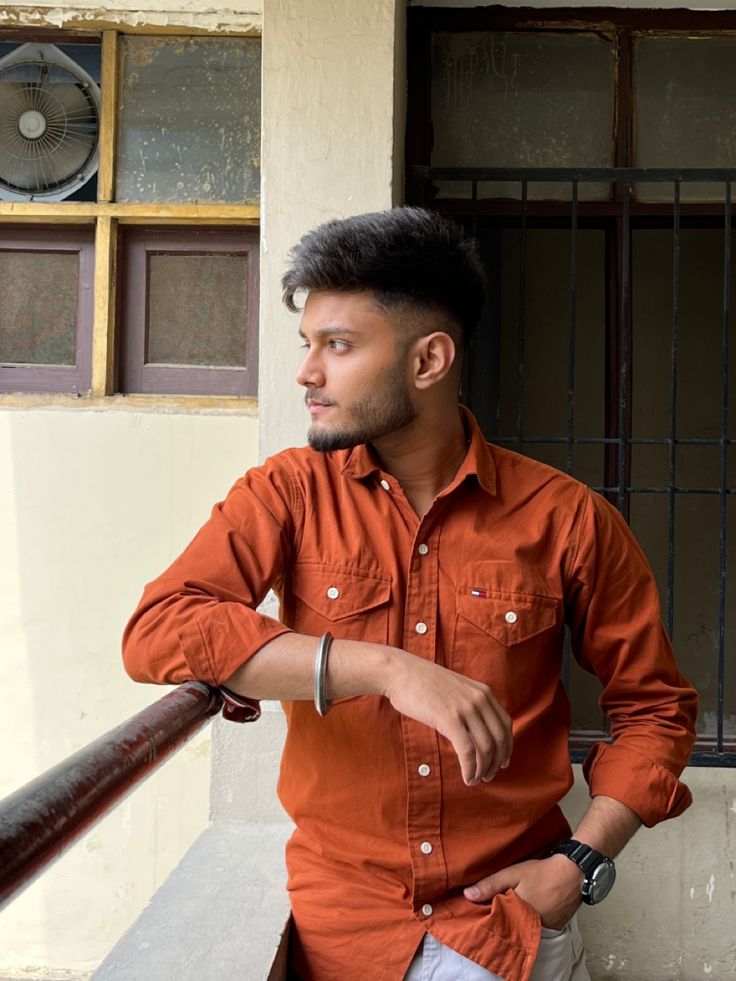 a man in an orange shirt leaning on a railing