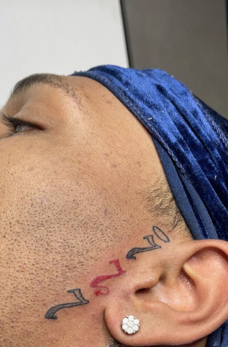 a man with tattoos on his face wearing a blue turban and piercings