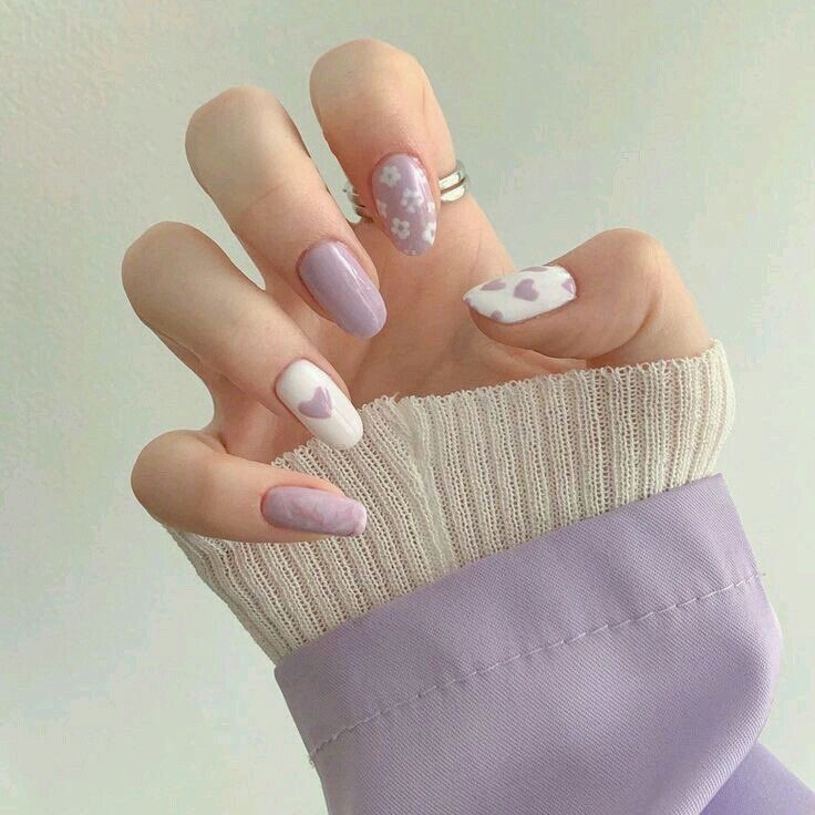 a woman's hand with pink and white manies on her nails, wearing a sweater