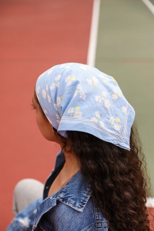 a woman sitting on a tennis court wearing a blue hat with daisies and white flowers