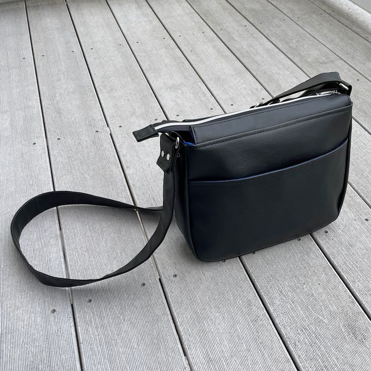 a black purse sitting on top of a wooden floor