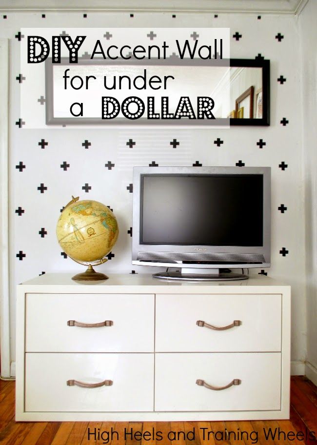 a tv sitting on top of a white dresser next to a wall with black crosses