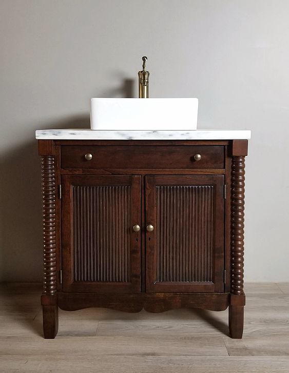 a bathroom sink sitting on top of a wooden cabinet next to a white countertop