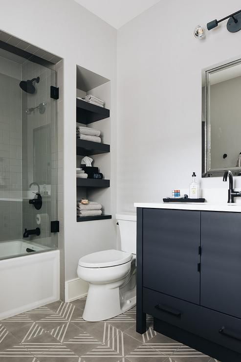 a white toilet sitting next to a bath tub under a bathroom mirror with black accents