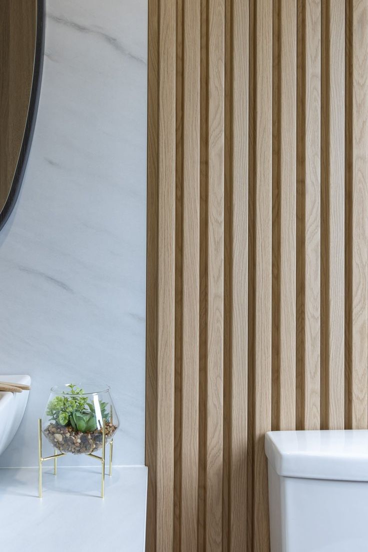 a white toilet sitting next to a wooden wall