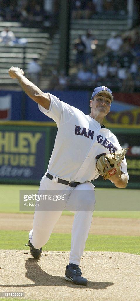 a baseball player pitching a ball on top of a field in front of a crowd