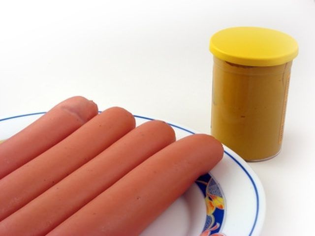 two hot dogs on a plate next to a jar of mustard