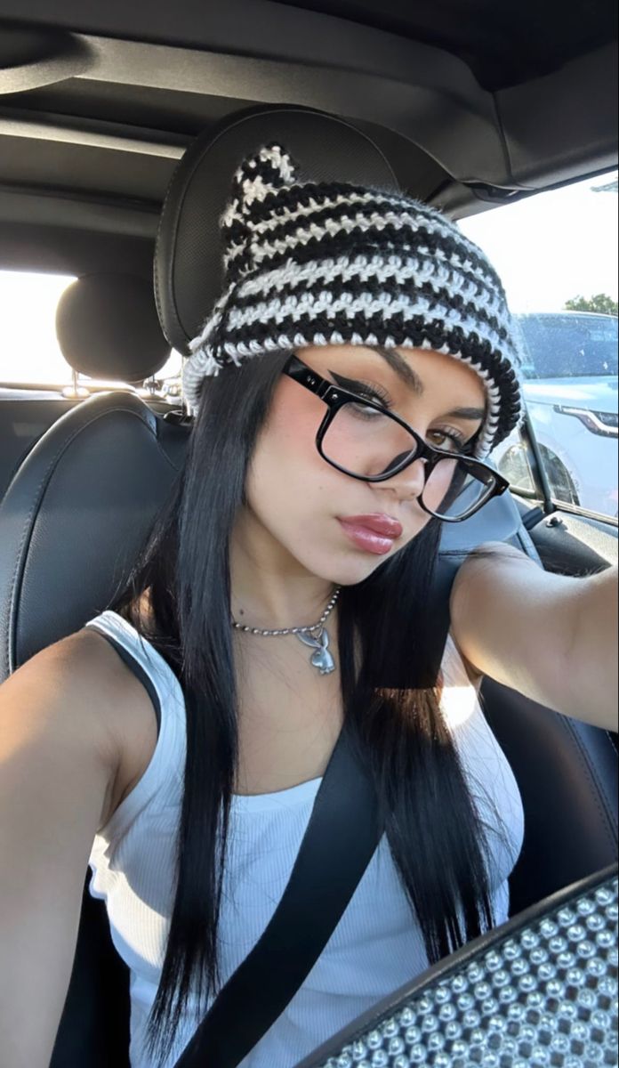 a woman sitting in the back seat of a car wearing a black and white hat