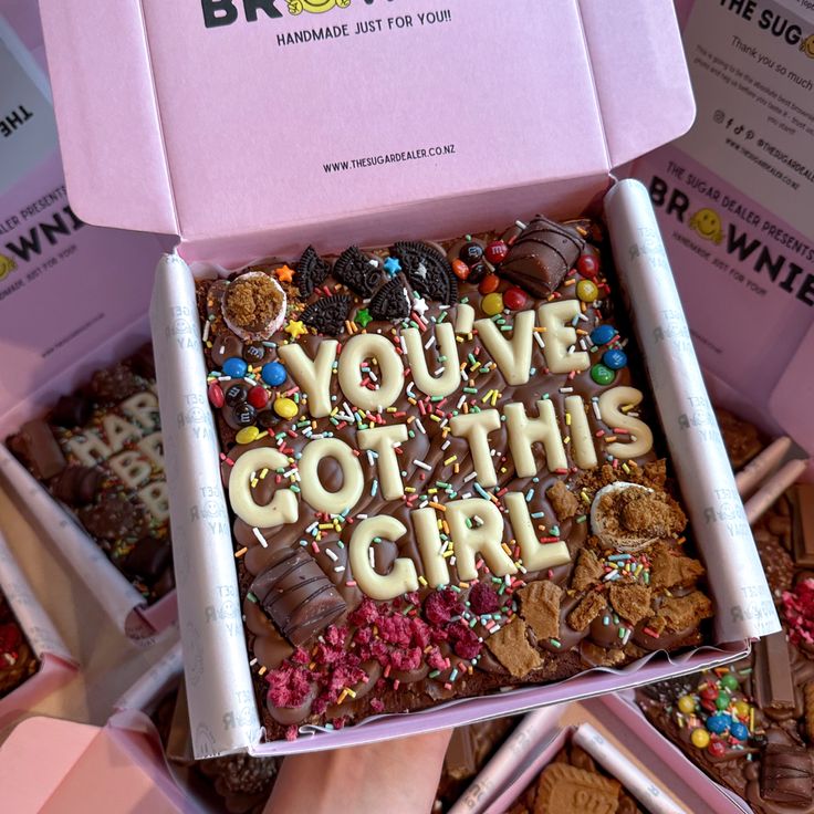 a pink box filled with lots of different types of cookies