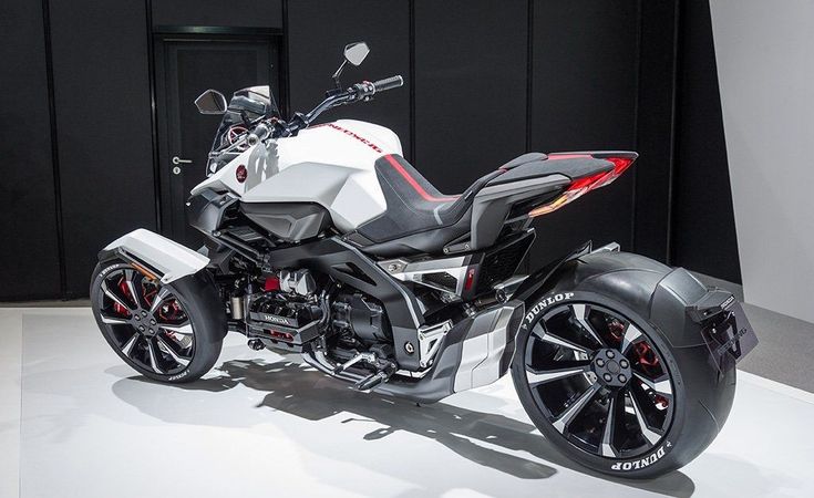 a white and black motorcycle parked in front of a building with red accents on it