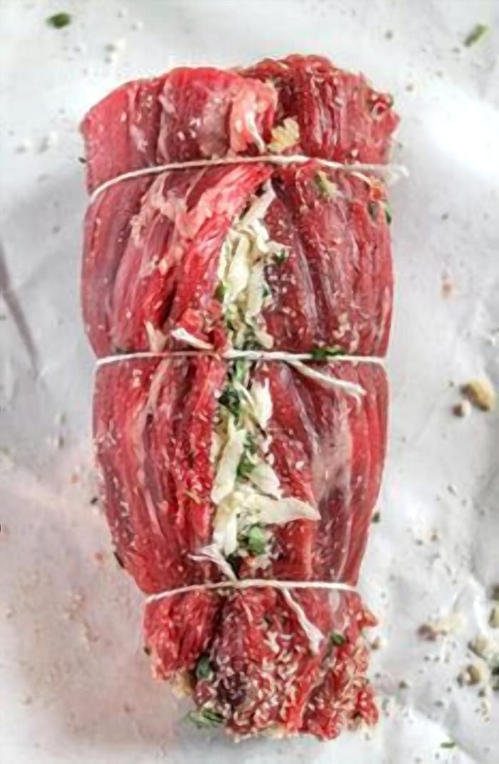 raw meat wrapped in plastic wrap sitting on top of paper