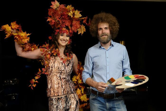 a man and woman dressed up in costumes holding paint palettes with leaves on them