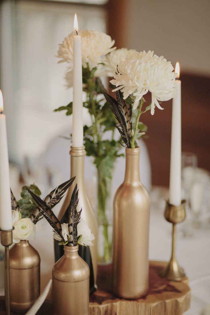 three vases with flowers and candles on a table