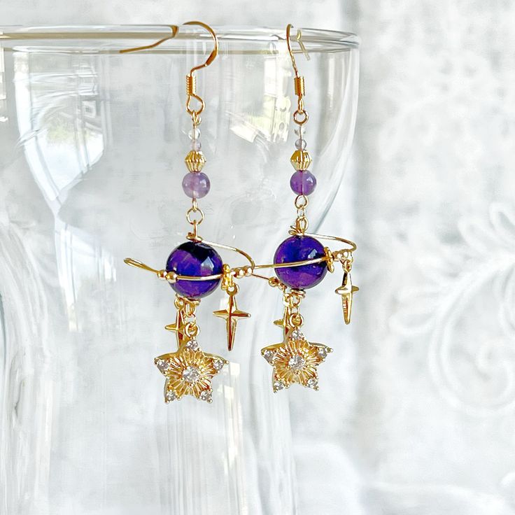 Amethyst Planet and Stars Earrings These stunning amethyst earrings feature an artistic and unique design of a planet and stars, expertly crafted from natural amethyst gemstones. Each pair is an original design handmade with great care and attention to detail. Make a statement with these beautiful earrings. As a gift shop, we offer a complimentary gift box for every order. Detail: Length of one earring - 60mm; size of beads - 5-10mm Material: ear wire - sterling silver; beads - natural Amethyst;  Note: the Amethyst Planet and Stars Earrings are handmade locally in the UK, each pieces would vary slightly in detail.  About postage: Standard postage When choosing standard postage, we assume this order is for yourself, or you will wrap the item yourself before giving it out as a gift (the comp Celestial Purple Dangle Earrings, Purple Celestial Dangle Earrings, Celestial Amethyst Purple Jewelry, Purple Amethyst Celestial Jewelry, Handmade Purple Celestial Earrings, Celestial Purple Amethyst Jewelry, Stars Earrings, Planet Earrings, One Earring