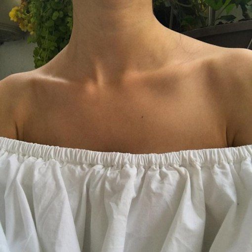 a close up of a woman's neck with flowers in the background