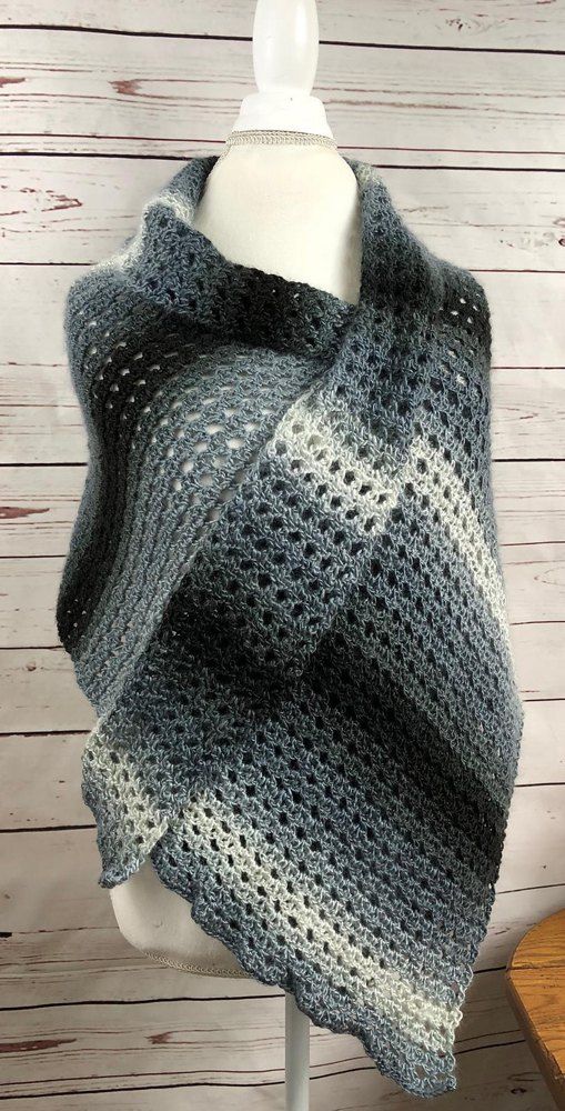 a gray and white knitted shawl on a mannequin