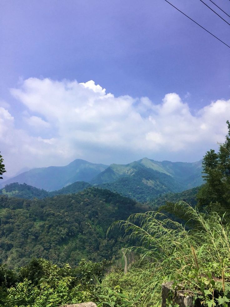 the mountains are covered with green vegetation and clouds in the sky, as well as power lines