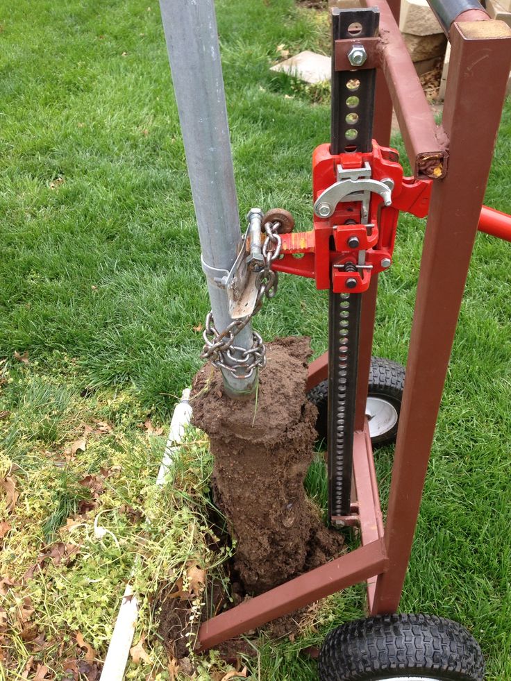 a red machine that is sitting in the grass next to a pole and some dirt