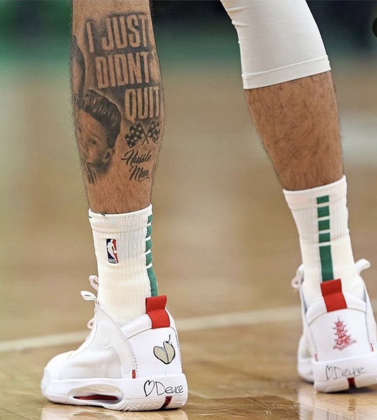 the legs and ankles of a basketball player with tattoos on his leg, wearing white sneakers