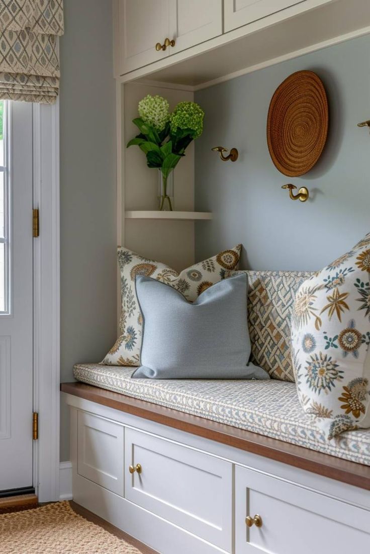 a window seat with pillows on it in front of a white door and some cupboards