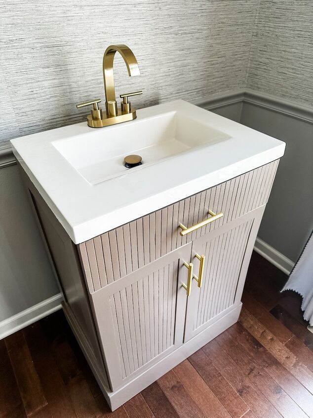 a white sink sitting on top of a wooden floor next to a wall mounted faucet