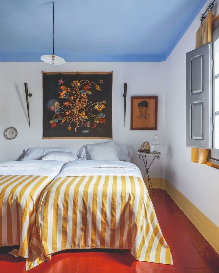 a bed sitting in a bedroom next to a window with an art hanging above it