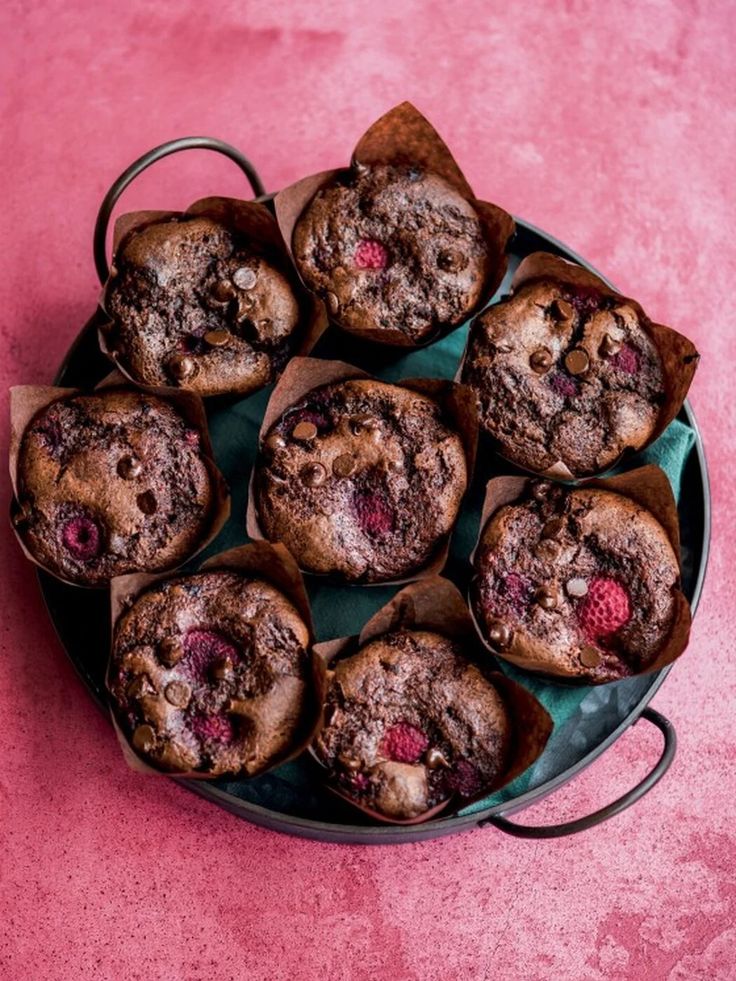 chocolate muffins with raspberries are on a blue plate and pink background