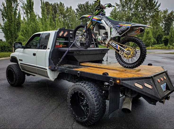 a white truck with a dirt bike on the back of it's flatbed