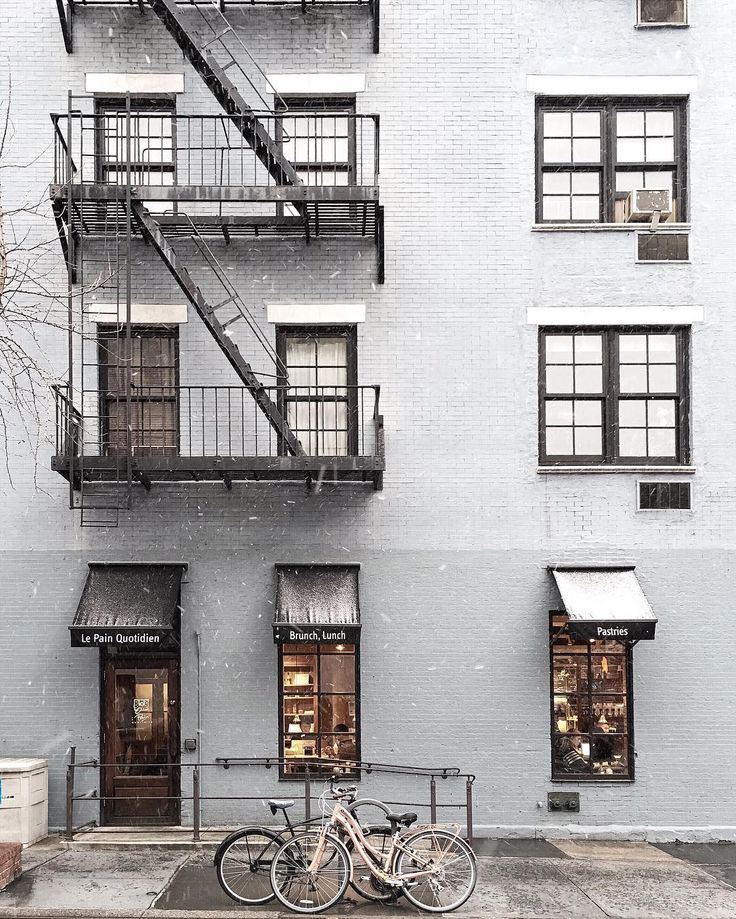 a bicycle is parked in front of a building on a street corner with stairs leading up to the second story