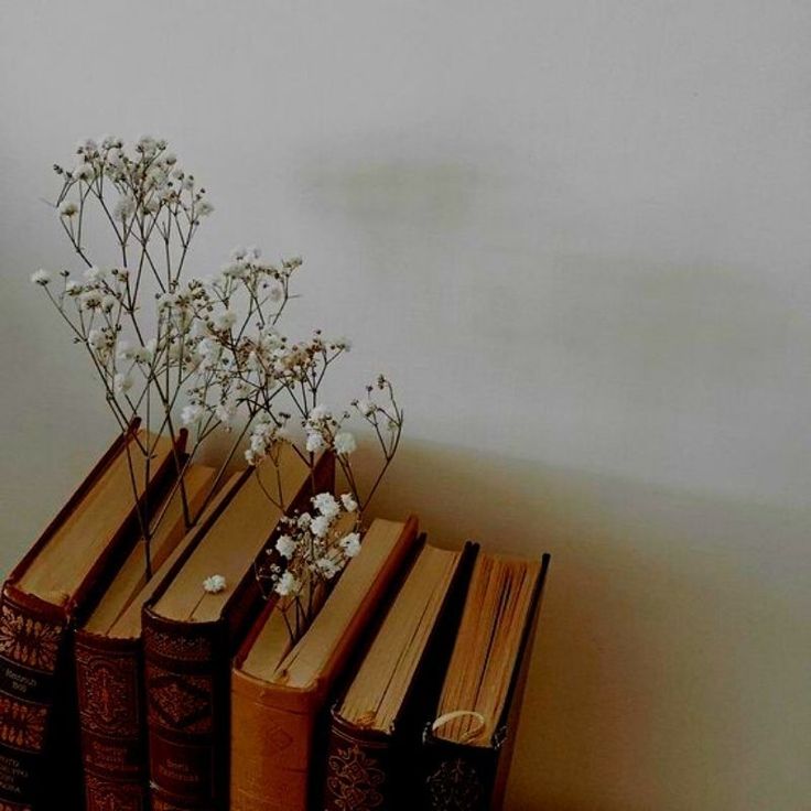 several books with flowers in them sitting on a table