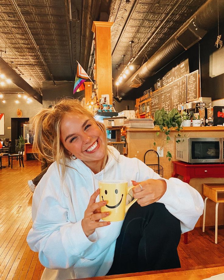 a woman holding a cup with a smiley face on it