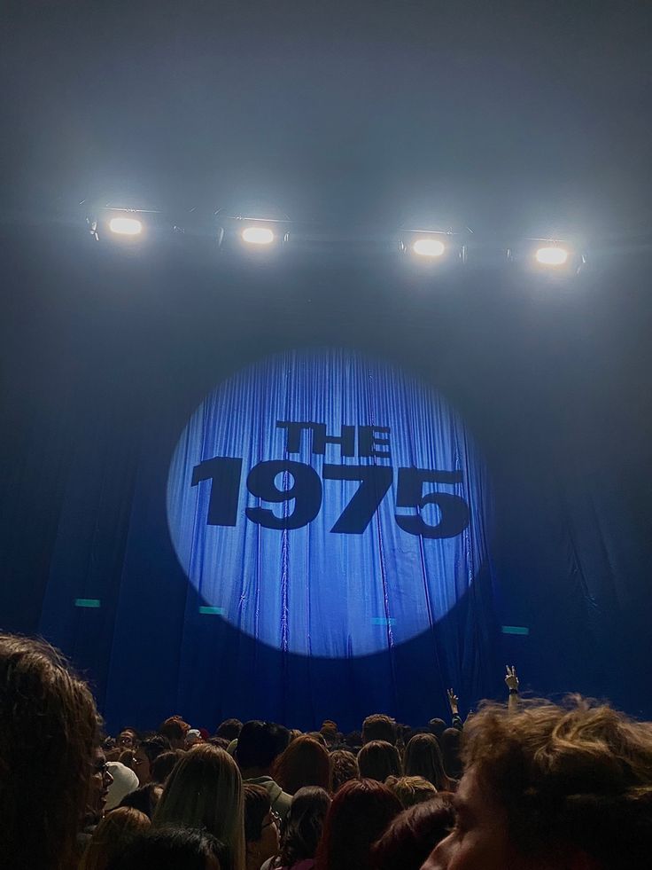 the stage is lit up with blue curtains and people are standing in front of it