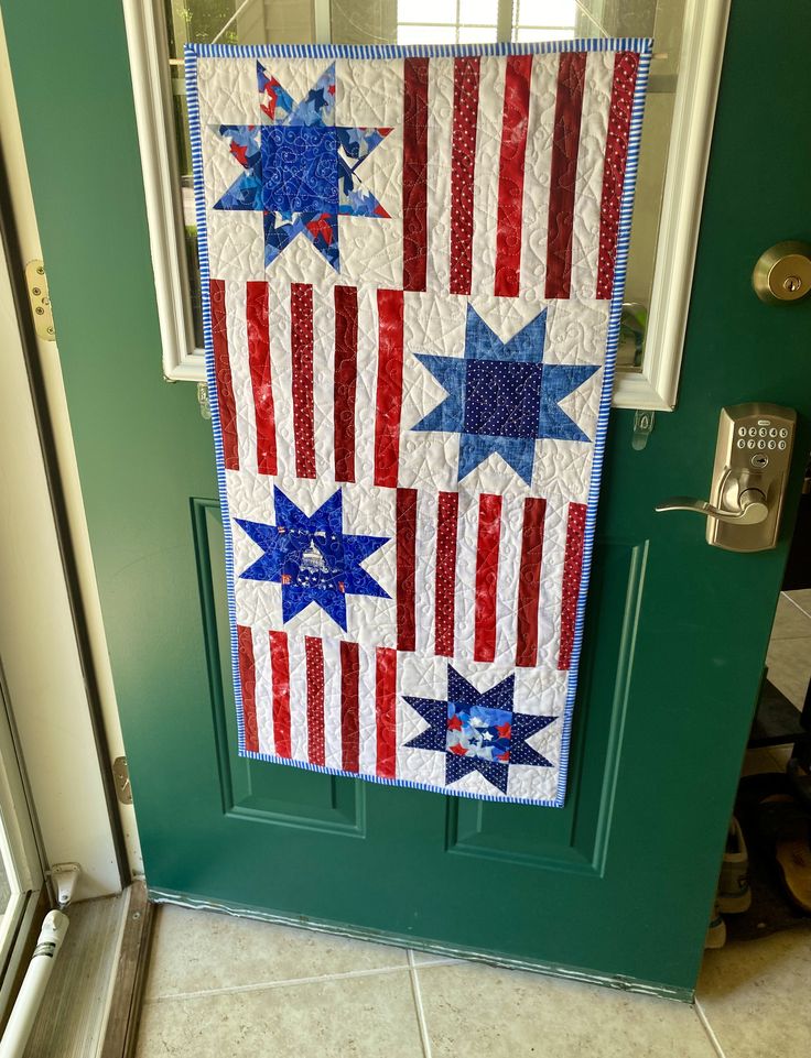 an american flag quilt hanging on the front door to show it's patriotic colors