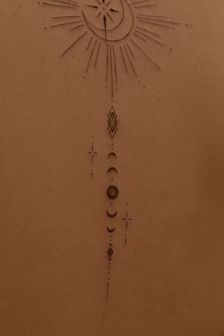 a tattoo on the back of a woman's upper body with symbols and stars